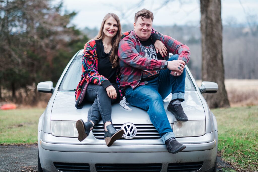 Katelyn and Danny sitting on a silver VW Jetta